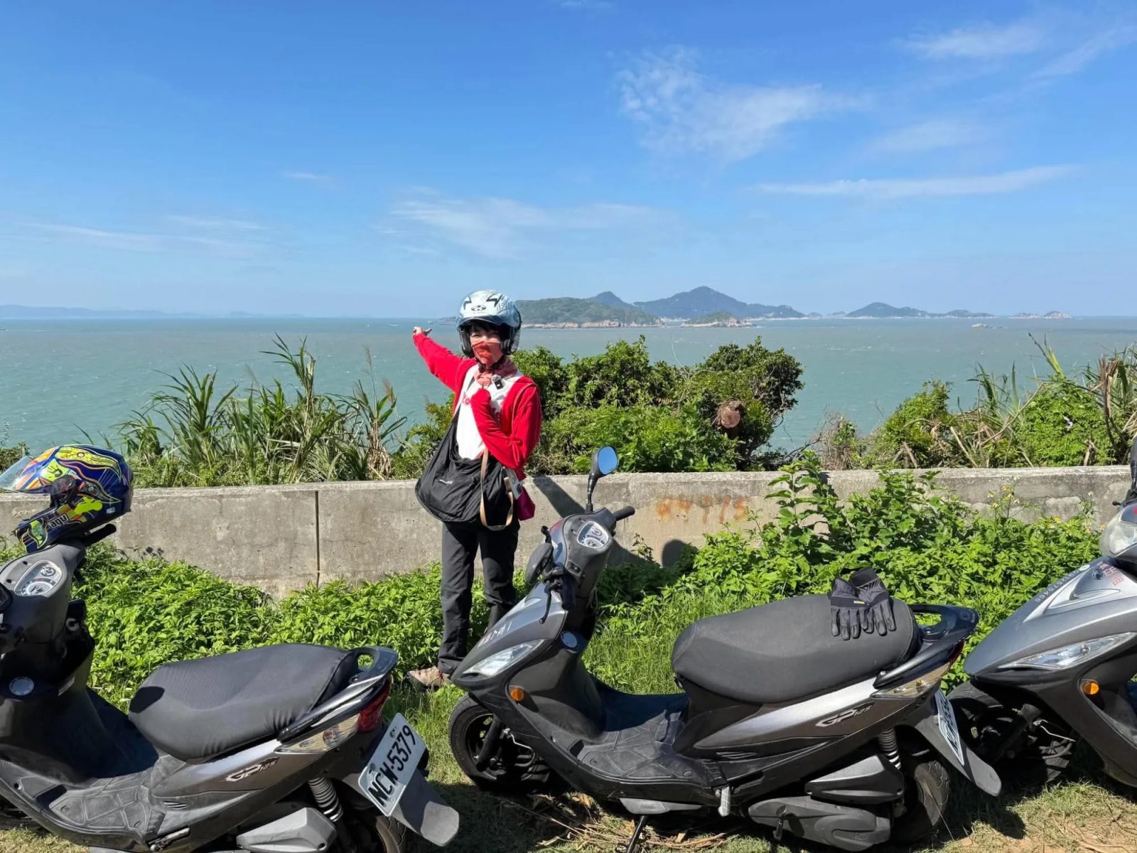 海と島々を望む高台で景色を指さす岸夏苗